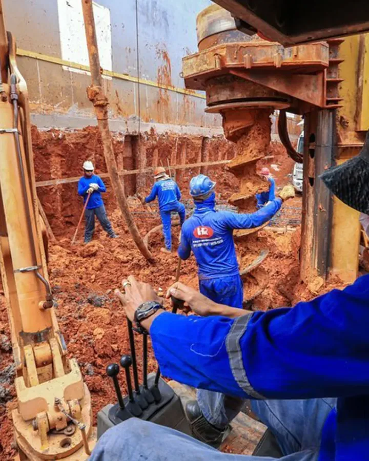 Trado escavando estaca em obra da HR Fundações em Brasília, com equipe posicionando a armadura